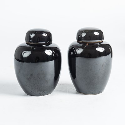 Lot 136 - A pair of black-glazed jarlets and covers